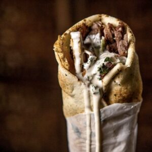 "Beef Shawarma Sandwich with marinated grilled meat, garlic sauce and fresh veggies in Lebanese bread"