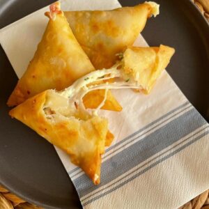 "Cheese Sambousek, crispy pastry triangles stuffed with melted cheese, perfect as appetizers or snacks."