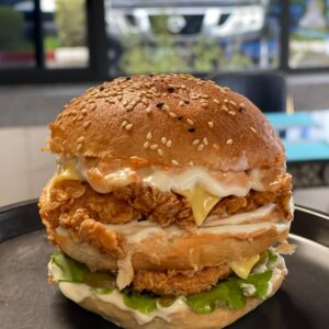 "Double Burger Poulet, un burger croustillant avec deux filets de poulet panés, sauce spéciale et fromage fondu, servi dans un pain brioché doré."